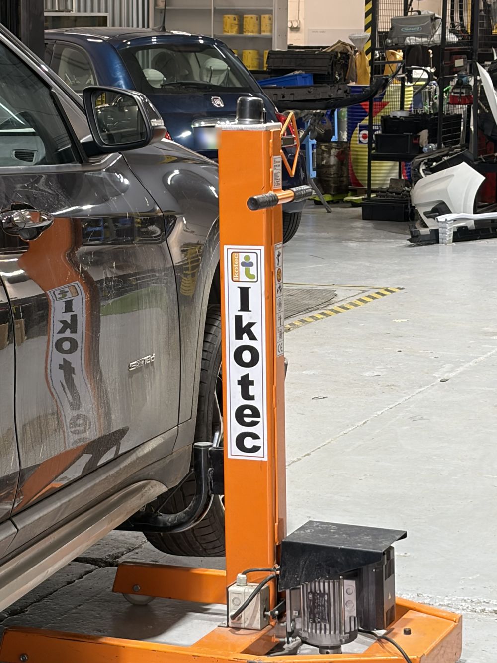 Equipo de tiro para reparar carrocería junto a un coche en el taller